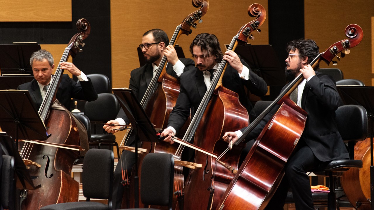 Quatro músicos de terno tocando violoncelo.