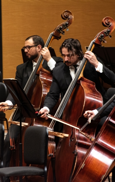 Quatro músicos de terno tocando violoncelo.