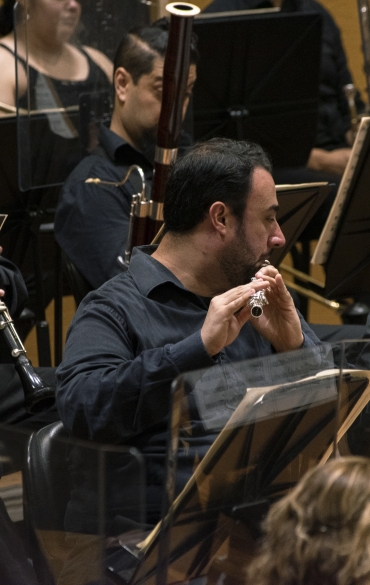 Vemos músicos da orquestra tocando instrumentos de sopro.