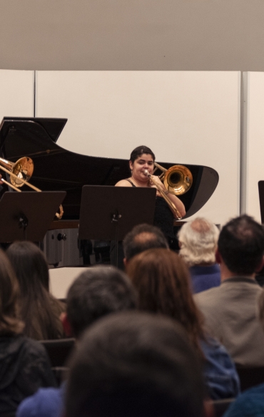 Vemos à esquerda o pianista Paulo Bergmann e os três trombonistas: José Milton Vieira, Sabryna Pinheiro e Rodrigo da Rocha, da esquerda para a direita. Vemos também parte da plateia.