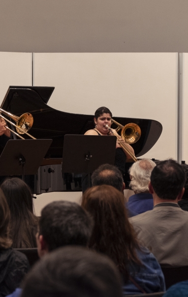 Vemos à esquerda o pianista Paulo Bergmann e os três trombonistas: José Milton Vieira, Sabryna Pinheiro e Rodrigo da Rocha, da esquerda para a direita. Vemos também parte da plateia.