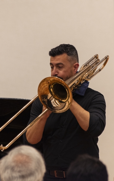 Vemos o trombonista Rodrigo da Rocha tocando.