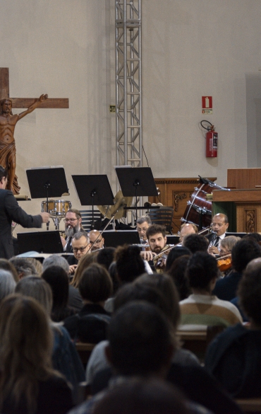 Vemos boa parte da plateia e, ao fundo, a orquestra e o maestro Evandro Matté.