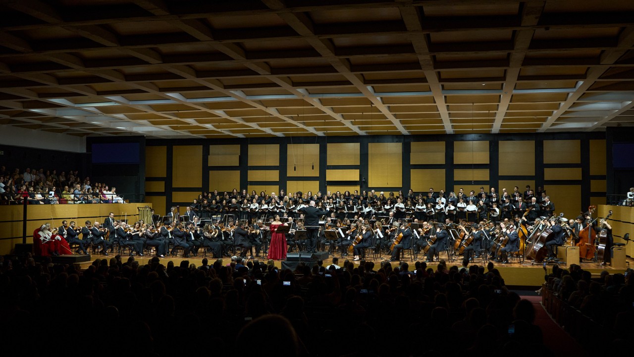 Imagem da orquestra e coro sinf&ocirc;nico na sala de concertos da Casa da OSPA durante o Concerto de Natal de 2025